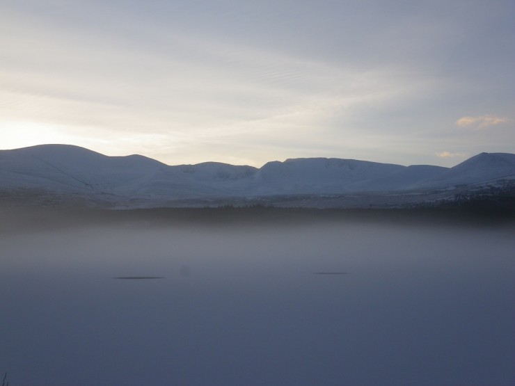Early morning light on the Cairngorms from a mist covered Loch Morlich